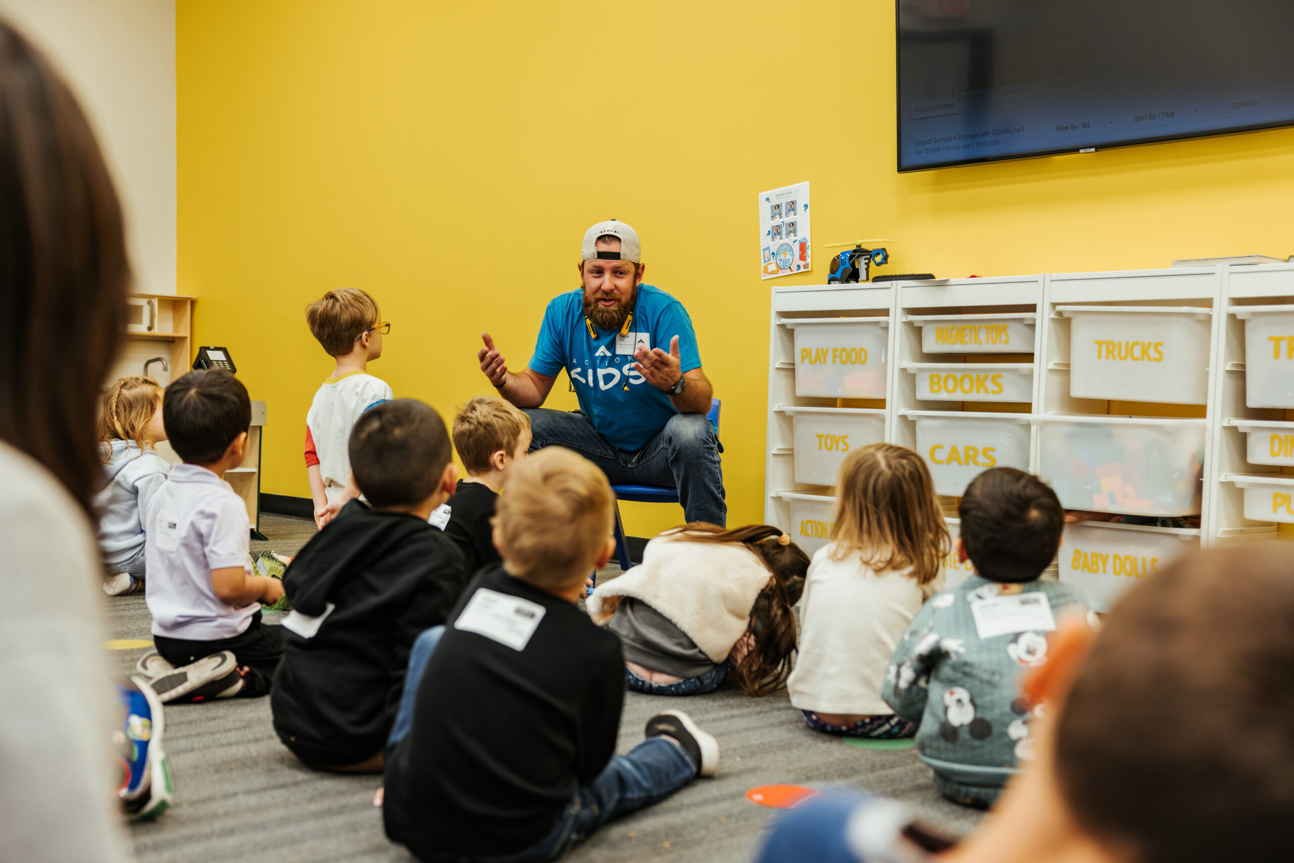 Action Kids volunteer talking with a group of children in a classroom