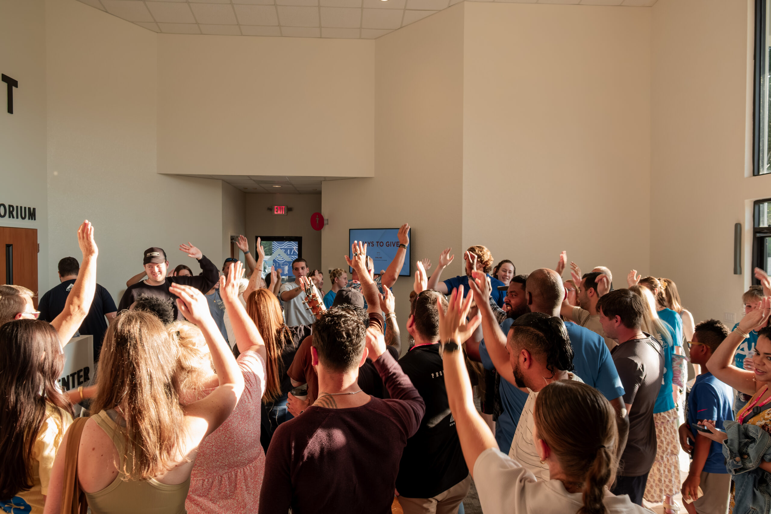 Congregation raising hands in worship at The Action Church