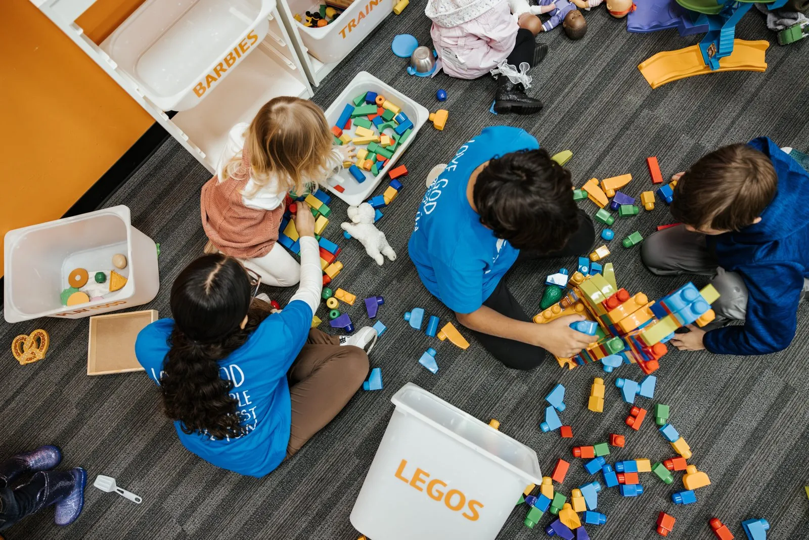 Action Kids volunteers and children playing with building blocks on the floor