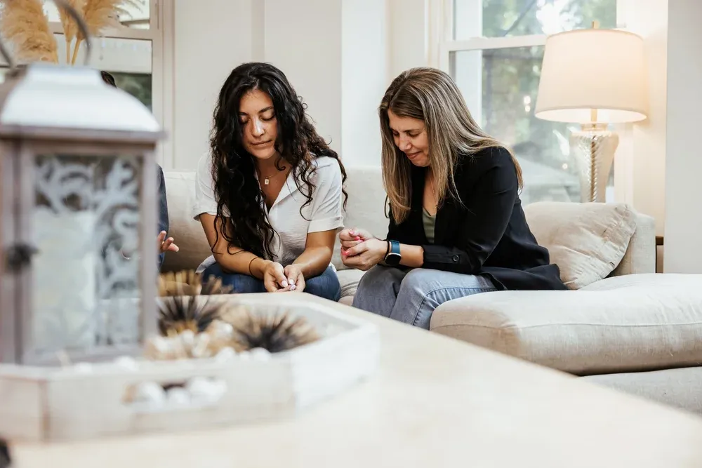 Two women sharing an authentic community moment on a couch