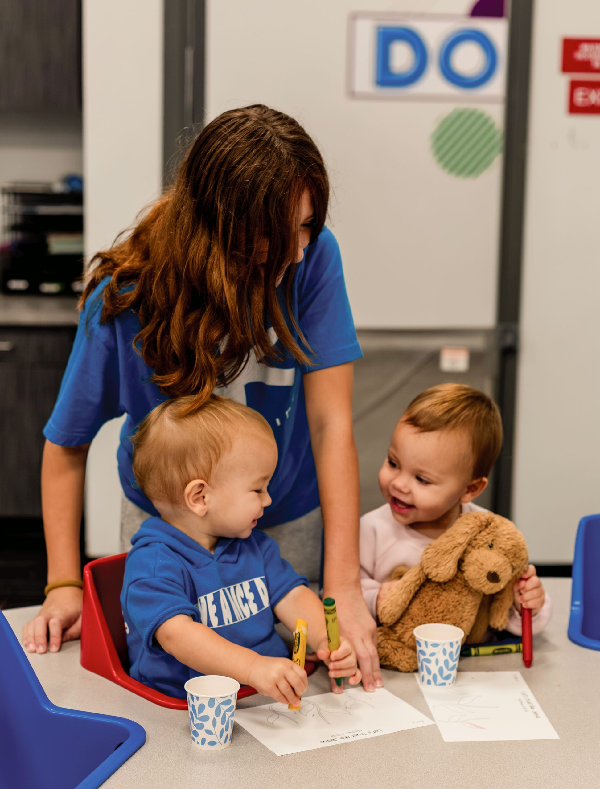 Action Kids volunteer coloring with toddlers at a table