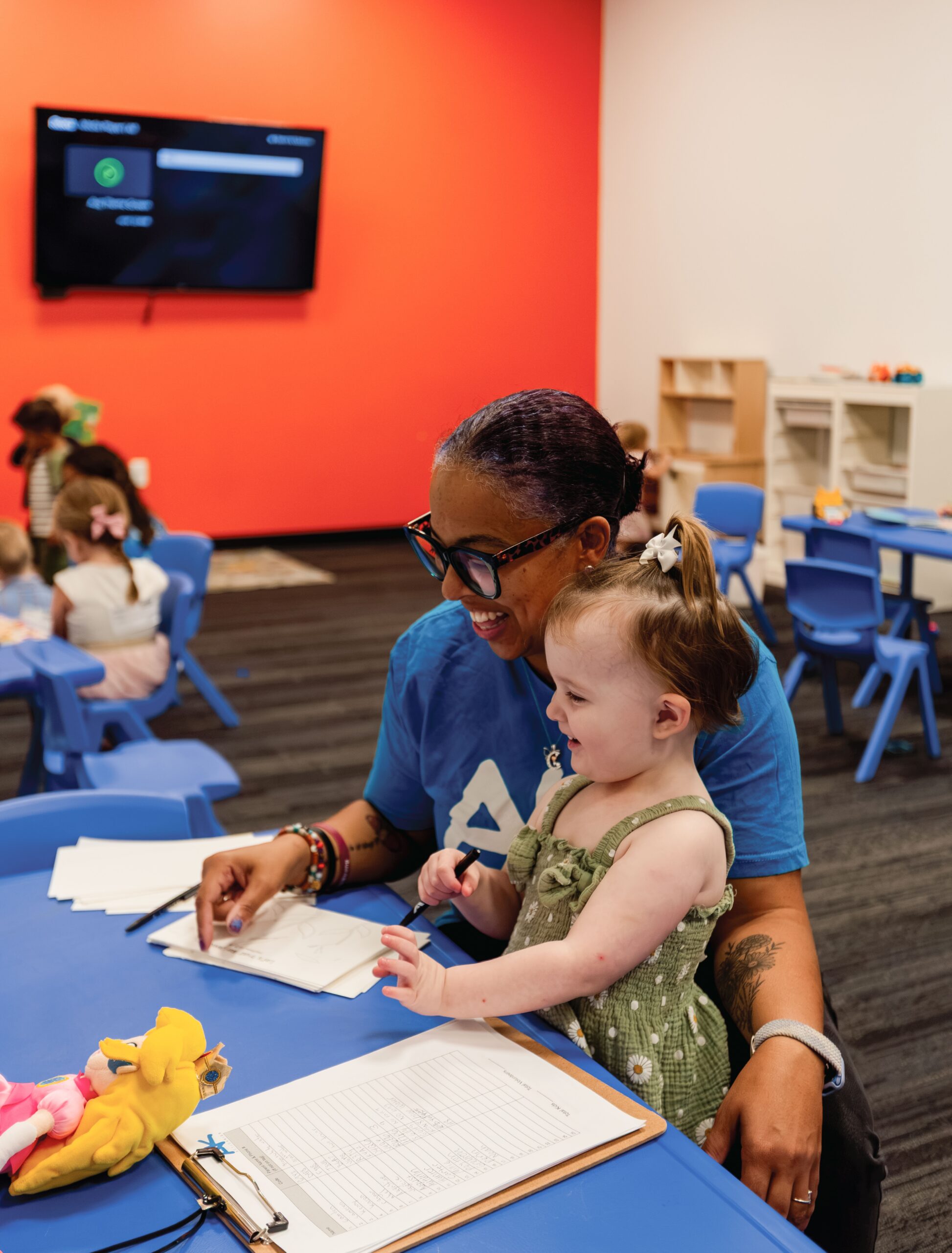 Action Kids volunteer helping a toddler with a craft