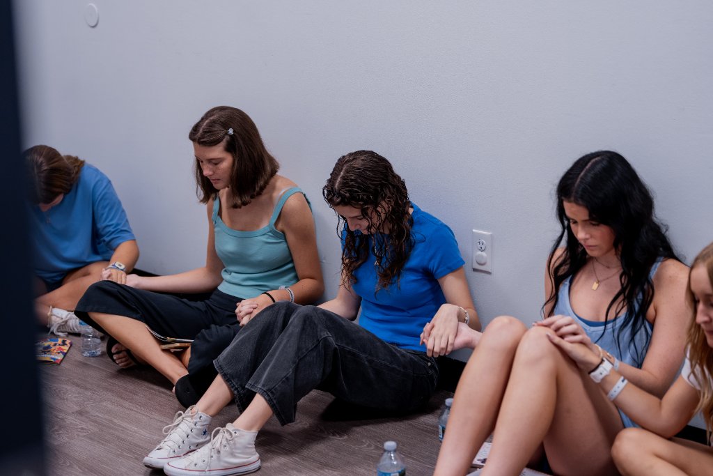 Young women praying together on the floor at an Action Church gathering